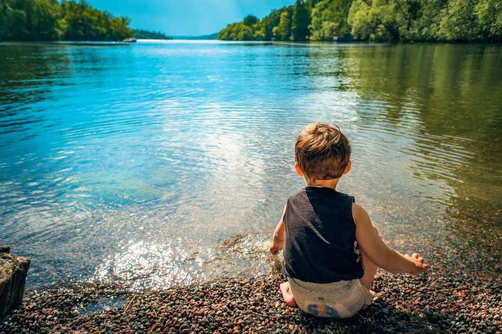 A boy sitting by a lake