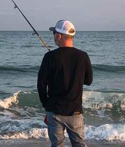picture of me on the beach holding a fishing rod