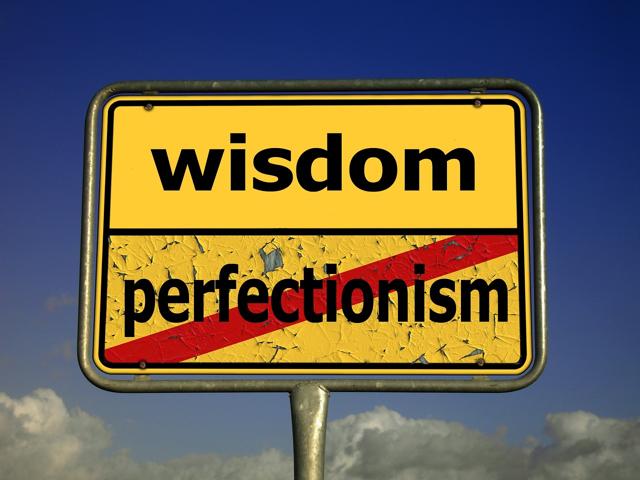 yellow caution road sign with the words wisdom and perfectionism and perfectionism is marked through with red paint