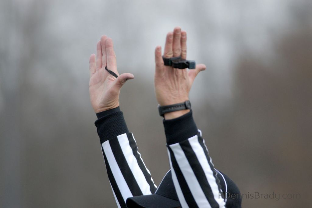 football umpire with hands raised signaling a touchdown